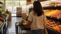 Adrianna pushes a cart with a watermelon through a bright produce aisle in summer.
